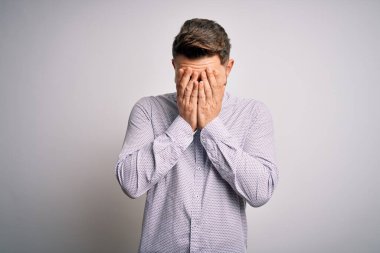 Mavi gözlü genç bir iş adamı, soyutlanmış arka planda duruyor. Ağlarken yüzünü ellerle kapatan üzgün bir yüz ifadesi var. Depresyon kavramı.