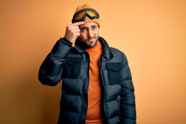 Kar giysileri ve kayak gözlüğü takan sakallı yakışıklı kayakçı alnındaki sivilceden mutsuz, siyah başlıklı, çirkin bir enfeksiyon taşıyor. Sivilce ve deri problemi