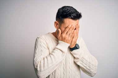 İzole edilmiş beyaz arka plan üzerinde duran sıradan süveter giyen genç yakışıklı bir adam. Ağlarken suratını ellerle kapatan üzgün bir ifade. Depresyon kavramı.