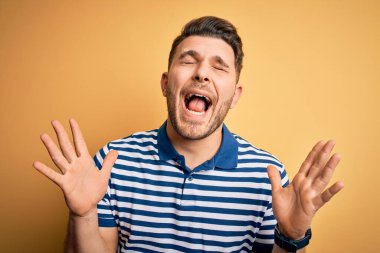 Sarı arka plan üzerine sıradan çizgili tişört giyen mavi gözlü genç adam başarıyı kutlarken kolları havada ve gözleri kapalı heyecanla bağırıyor. Kazanan konsept