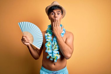 Tatilde olan genç turist mayo giyiyor ve Hawaii çiçekleri elinde yelpaze tutuyordu. Ağzı el kapağıyla kaplıydı. Yanlışlıkla ağızdan okunuyordu.