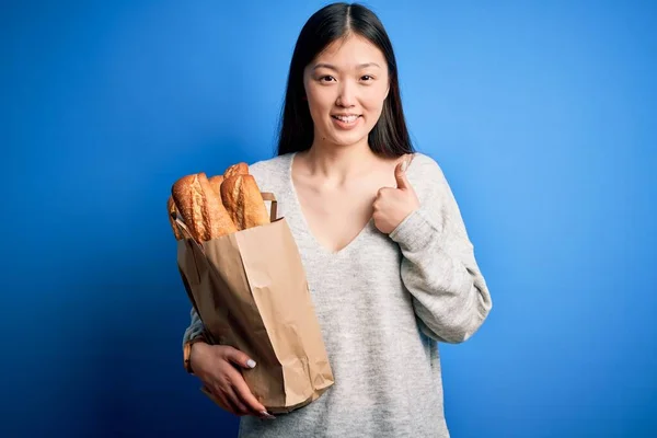 Jovem Asiático Mulher Segurando Pão Supermercado Papel Saco Sobre Azul — Fotografia de Stock