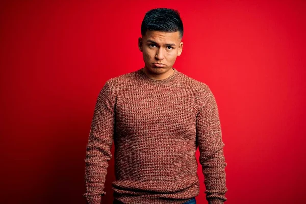 赤い背景の上に立ってカジュアルなセーターを着て若いハンサムなラテン人落ち込んで 苦痛のために心配し 怒っていると恐れて泣いている 悲しい表情 — ストック写真