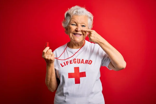 年长美丽的灰白头发的救生员女人穿着印有红十字图案的T恤衫 手指手画脚 面带微笑 美的概念 — 图库照片