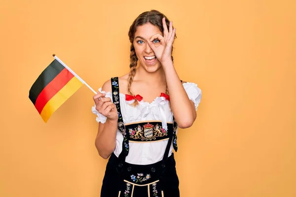美しいですブロンド愛国的な女性とともに青い目を身に着けています10月祭のドレス保持ドイツ語の旗とともに幸せな顔笑顔Doing Signで手で目を通して指を見て — ストック写真