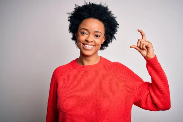 赤いカジュアルなセーターを着て巻き毛を持つ若い美しいアフリカ系アメリカ人アフロ女性は笑顔と指を見てとカメラと小さなサイズの看板を行う手で自信を持ってジェスチャー 概念の測定 — ストック写真