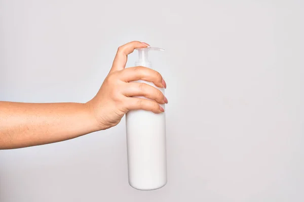 白い背景の上にボディクリームのボトルを保持している白人若い女性の手 — ストック写真