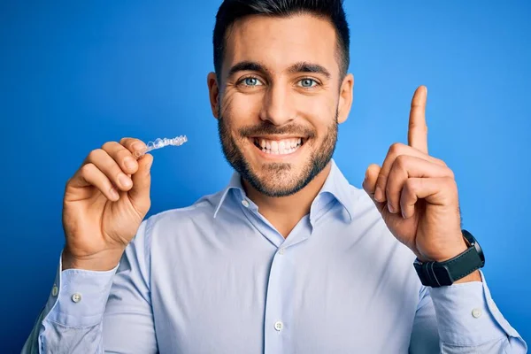 Junger Gutaussehender Mann Mit Zahnausrichterzahnkorrektur Vor Blauem Hintergrund Überrascht Mit — Stockfoto