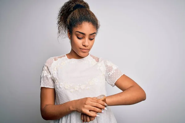 若いです美しいですアフリカ系アメリカ人の女の子身に着けていますカジュアルTシャツ上の白い背景を立って手首の腕時計で時間をチェック リラックスして自信 — ストック写真