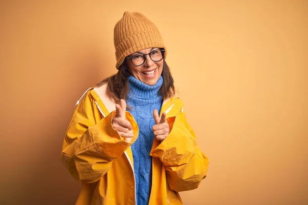 Middelbare Leeftijd Vrouw Met Gele Regenjas Wintermuts Geïsoleerde Achtergrond Wijzende — Stockfoto