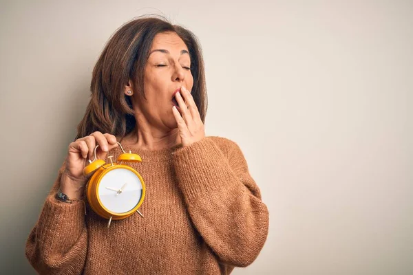 孤立した背景に古典的な目覚まし時計を保持している中世のブルネットの女性は 手で疲れカバー口をあくび退屈 眠れないのか — ストック写真