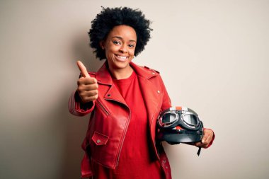 Kıvırcık saçlı, motosiklet kaskı takan genç Afrikalı Afrikalı motosikletçi kadın el hareketleriyle olumlu jest yapmayı onaylıyor, gülümsüyor ve başarı için seviniyor. Kazanan jest.