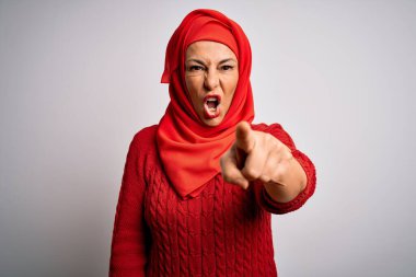 Orta yaşlı esmer kadın izole edilmiş beyaz arka plan üzerine geleneksel başörtüsü takıyor. Kameraya kızgın ve sinirli olduğunu gösteriyor.
