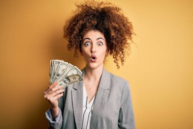 Kıvırcık saçlı ve elinde dolar banknotları olan genç ve güzel bir kadın. Şaşırmış bir yüzle korkmuş ve korku ifadesinden heyecanlanmış.