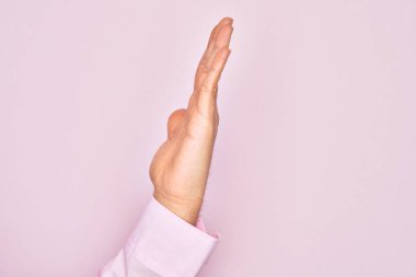 Kafkasyalı bir gencin elleri pembe arka planda parmaklarını gösteriyor. Uzanmış el hareketlerini gösteriyor, itiyor ve duruyor.