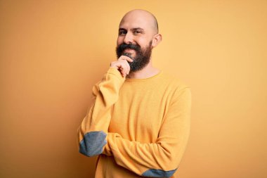 Sarışın, sakallı, sıradan bir süveter giyen, kameraya kendinden emin, kolları çapraz ve çenesi açık bakan yakışıklı bir adam. Olumlu düşünüyorum..