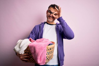 Genç yakışıklı adam ev işi yapıyor hasırdan sepet tutuyor, mutlu yüzlü, gülümseyen, tamam işaret veriyor, parmaklarının arasından bakıyor.