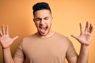 İzole edilmiş sarı arka plan üzerinde dikilmiş kollarını kaldırmış, gözlerini kapatmış heyecanlı çığlıklar atarak başarıyı kutlayan genç ve yakışıklı bir adam. Kazanan konsept