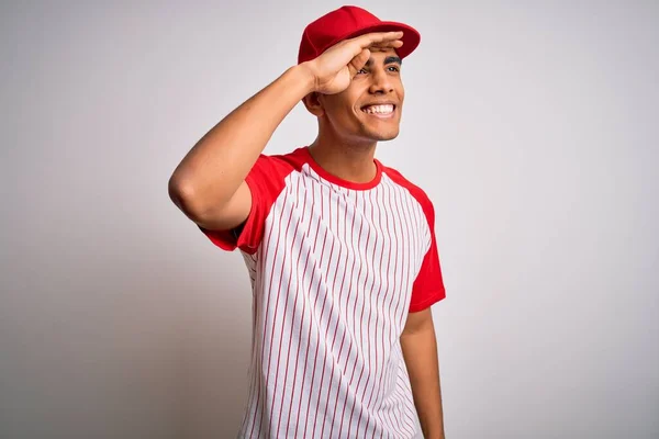 若いハンサムなアフリカ系アメリカ人のスポーツマンは ストライプの野球Tシャツを着て 頭の上に手で遠くを見て非常に幸せと笑顔キャップ 検索の概念 — ストック写真