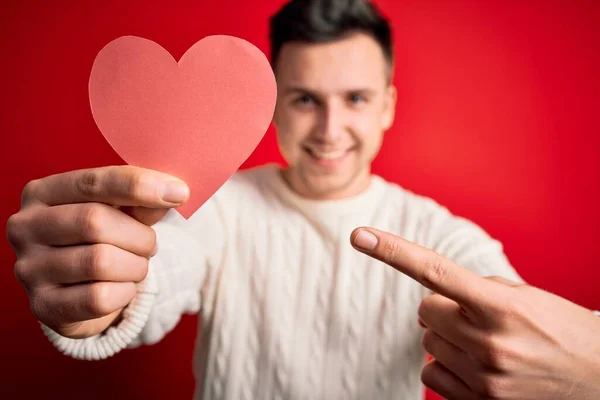 Jovem Bonito Caucasiano Homem Segurando Papel Forma Coração Sobre Vermelho — Fotografia de Stock