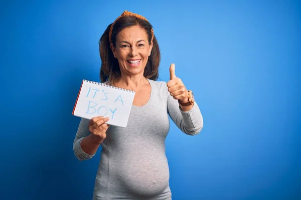中年妊娠中の女性期待して赤ん坊男の子上の青の背景幸せなです大笑顔行いますOkサイン 親指アップとともに指 優れたサイン — ストック写真