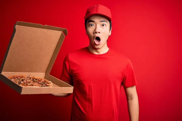 若いですハンサムな中国の配達人は驚きの顔でショックで怖がっておいしいイタリアのピザと箱を提供保持します 恐怖の表現で恐れと興奮 — ストック写真