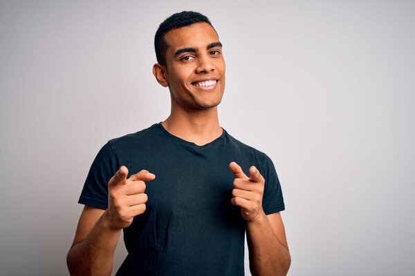 Young handsome african american man wearing casual t-shirt standing over white background pointing fingers to camera with happy and funny face. Good energy and vibes.
