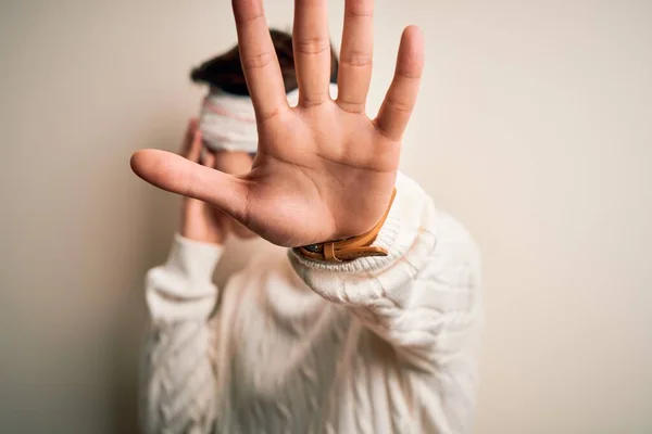 Young handsome chinese man injured for accident wearing bandage and strips on head covering eyes with hands and doing stop gesture with sad and fear expression. Embarrassed and negative concept.