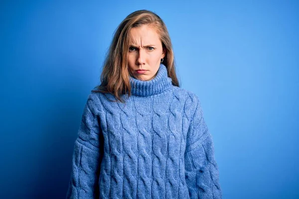 Young beautiful blonde woman wearing casual turtleneck sweater over blue background skeptic and nervous, frowning upset because of problem. Negative person.