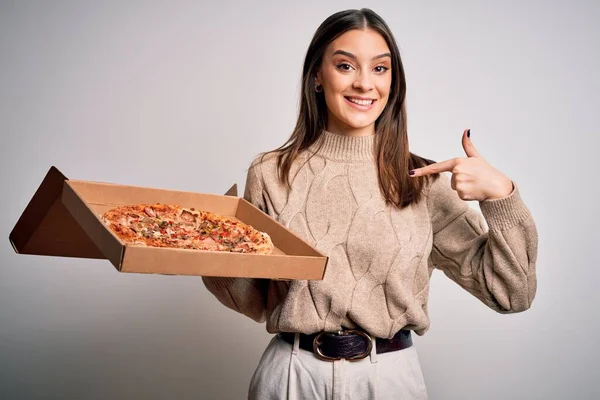 年轻美丽的黑发女子拿着装有意大利披萨的盒子 背景洁白 满脸惊讶 手指指向自己 — 图库照片