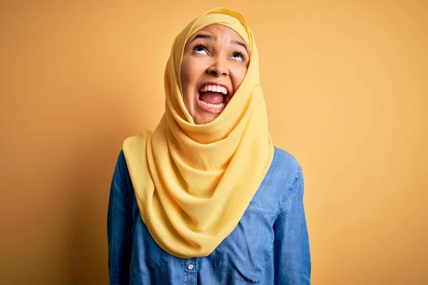 巻き毛を身に着けている若い美しい女性黄色の背景怒っていると怒っている叫び不満と激怒し 怒りで叫んで アラブの伝統的なヒジャーブ 激怒と積極的な概念 — ストック写真