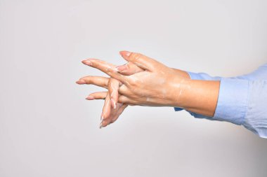 Beyaz arka planda alkol sıvısıyla el temizleyen genç beyaz kadın.