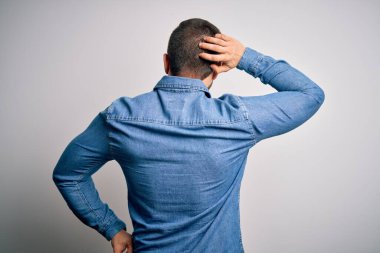 Sakallı, mavi gözlü, sıradan bir kot gömlek giyen genç, yakışıklı sarışın adam. Geriye dönüp, elleri kafasında şüpheyi düşünüyor.