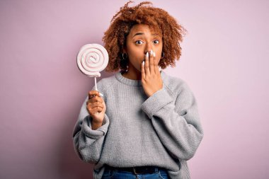 Kıvırcık saçlı, şeker kaplı ağızlı, elleri utançla sarsılan, korkuyu ifade eden, sessizlikten korkan kıvırcık saçlı, genç afro kadın.