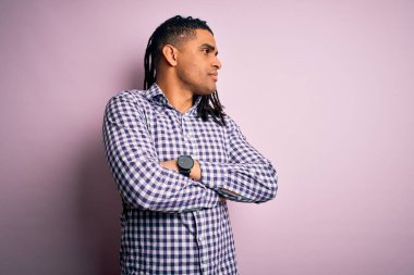 Rastgele gömlek giyen, kollarını kavuşturmuş, ikna olmuş ve kendinden emin genç, Afro-Amerikan bir adam.