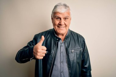 Üst düzey yakışıklı beyaz arka planda günlük gömlek ve ceket giyen yaşlı beyaz adam mutlu bir el hareketi yapıyor. Kameraya bakıp başarıyı gösteren ifade onaylanıyor.