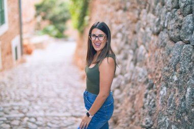 Mutlu ve kendinden emin gülümseyen genç ve güzel bir kadın. Kasaba caddesinde yüzünde gülümsemeyle dikilirken