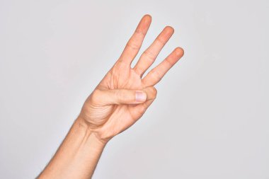 Beyaz arka planda parmaklarını gösteren beyaz tenli bir gencin eli üç parmağı gösteriyor.