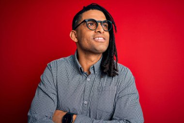 Rastgele gömlek ve gözlük takmış, yüzünde gülümsemeyle yan yana bakan Afro-Amerikan genç ve yakışıklı bir adam. Kendinden emin gülen.