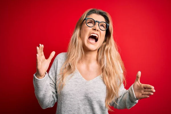 Jovem Mulher Loira Bonita Vestindo Suéter Óculos Sobre Fundo Vermelho — Fotografia de Stock