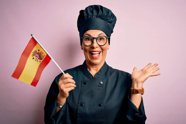 中年爱国女厨师 身穿炊事服 头戴西班牙色彩旗 喜形于色 喜形于色 喜形于色 喜形于色 喜形于色 高举双手庆祝胜利 — 图库照片