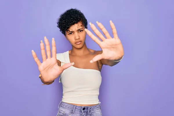 若い美しいアフリカ系アメリカ人のアフロ女性が紫色の背景にカジュアルなTシャツを着て手のひらと指を使ってフレームを行う カメラの視点 — ストック写真
