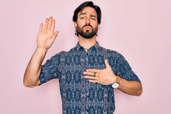 Yakışıklı İspanyol bohem bir adam pembe arka plan üzerinde hippi tarzı giyinmiş göğsü ve avucu açık yemin ederek sadakat yemini ediyor.