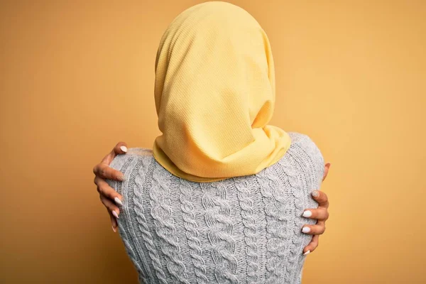 孤立した黄色の背景にイスラム教徒のヒジャーブを身に着けている若い美しいアフリカ系アメリカ人の少女自分自身を後方から幸せと肯定的な抱擁 自己愛と自己ケア — ストック写真