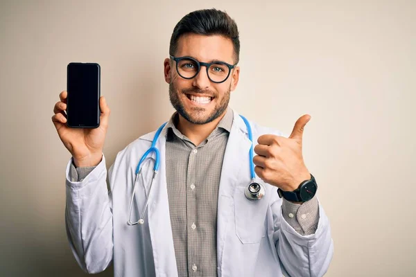 Młody Lekarz Noszący Stetoskop Pokazujący Ekran Smartfona Odizolowanym Tle Szczęśliwy — Zdjęcie stockowe