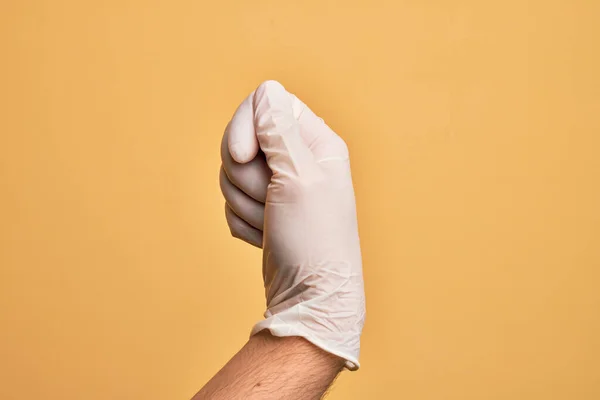 Mão Homem Jovem Caucasiano Com Luva Médica Sobre Fundo Amarelo — Fotografia de Stock