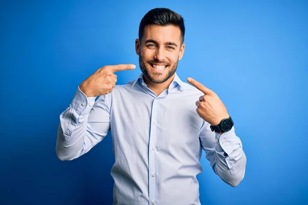 孤立した青い背景の上に立ってエレガントなシャツを着て若いハンサムな男は陽気に見せて笑顔と指の歯と口で指しています 歯科衛生の概念 — ストック写真