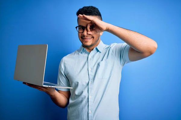 若いですハンサムなビジネスマン身に着けている眼鏡を使用して作業ノートパソコン上の青の背景と幸せな顔笑顔をします — ストック写真