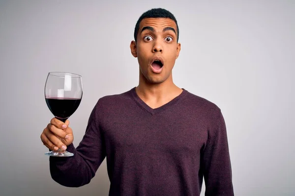 驚きの顔でショックで怖がっている白い背景に赤いワインのガラスを試飲ハンサムなアフリカ系アメリカ人ソムリエ男 恐れと恐怖の表現で興奮 — ストック写真