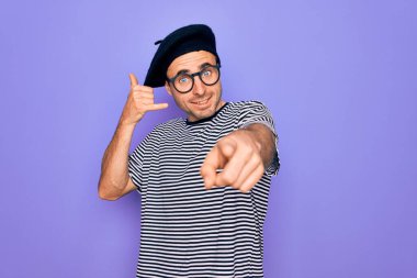 Mor arka planda çizgili tişört ve Fransız beresi giyen yakışıklı adam gülümsüyor telefonda konuşarak seni işaret ediyor. Ara beni..